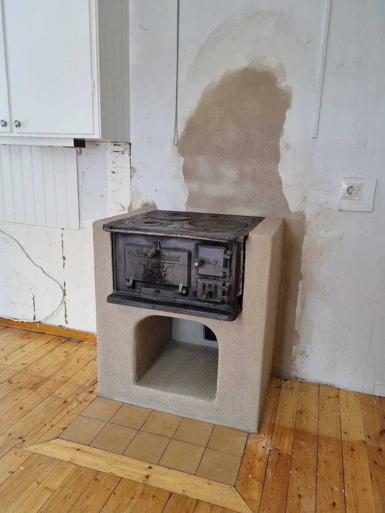 Restaurerad gjutjärnsvedspis på murad sockel